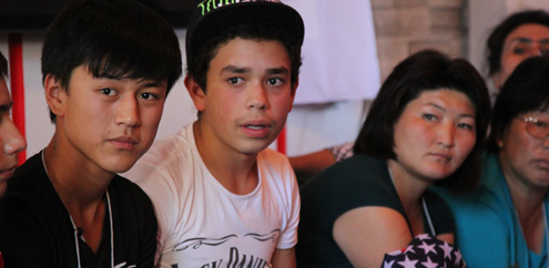 Male students Saliyar Mambetaliev (left) and Dilshat Mashanlo (second from the left) sit with their peers and teacher during a gender roles exercise.