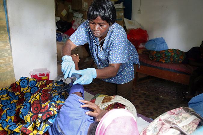 Midwife Lorina Karway attends to a new mother in the post-partum ward of the Bodowhea Clinic in River Cess Liberia. Photo: UN Women/Winston Daryoue