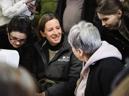 A woman wearing a UN Women jacket sits with Ukranian women
