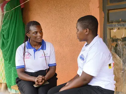 A young Ugandan woman sits with another local woman to talk