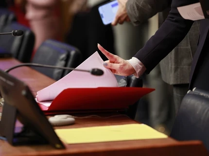 A woman's hand flips through paperwork at the UN
