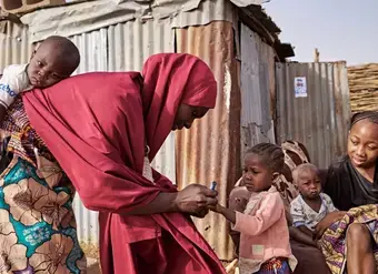 A woman delivers a vaccine to a small child