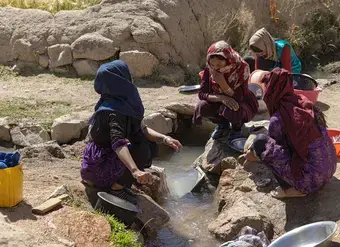 Afghan women gathered together and washing cookware