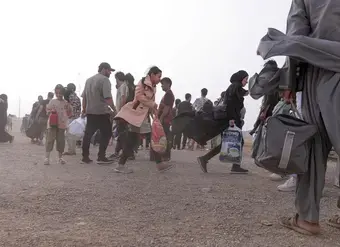 Women and young girls carry bags after crossing the border
