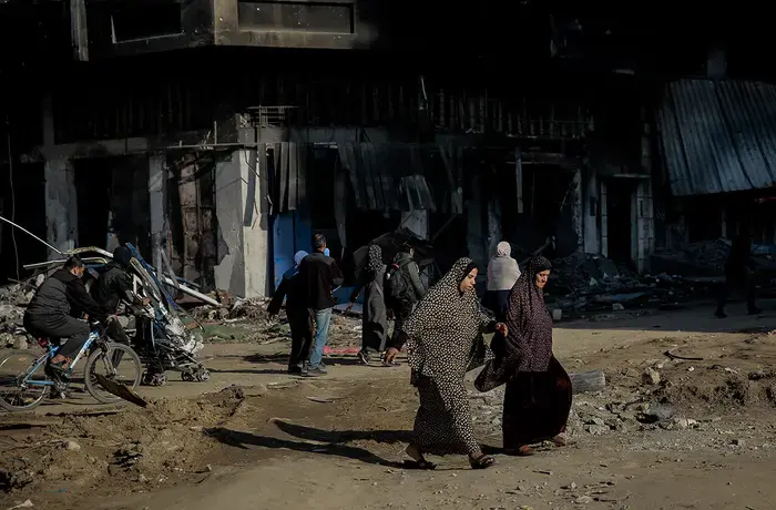 Two women cross the road and are surrounded by destroyed buildings on al-Jalaa Street in the centre of Gaza City on 11 January 2024. 