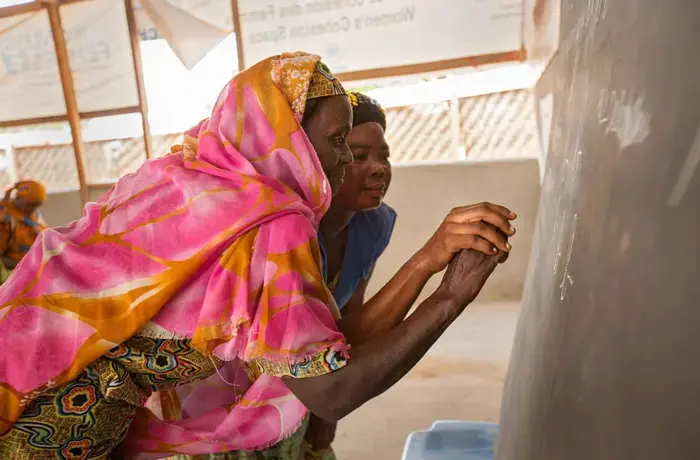 A refugee fromCentral African Republic (CAR) learns the French alphabet as part of an adult education class held at the UN Women Social Cohesion space. Refugees from CAR speak a variety of languages, and many seek to learn French, one of Cameroon’s official languages, in order to integrate successfully. Photo: UN Women/Ryan Brown