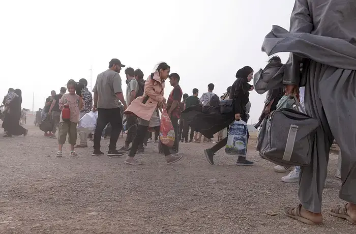 Women and young girls carry bags after crossing the border
