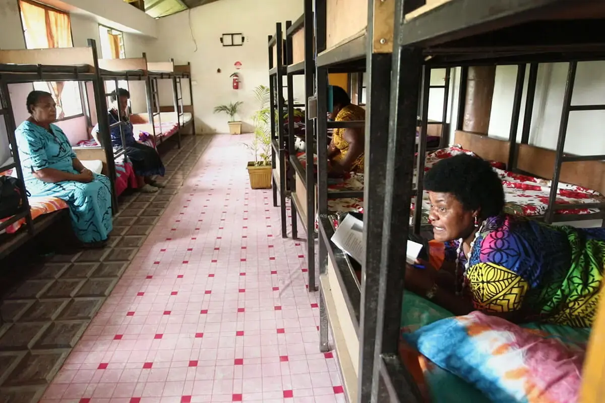 Women sit in bunk beds in a large, clean room