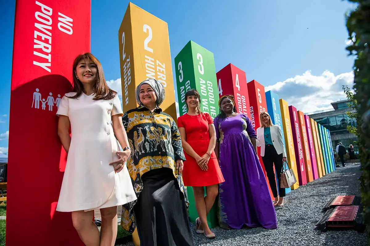 Brightly dressed women stand together in front of the UN General Assembly building