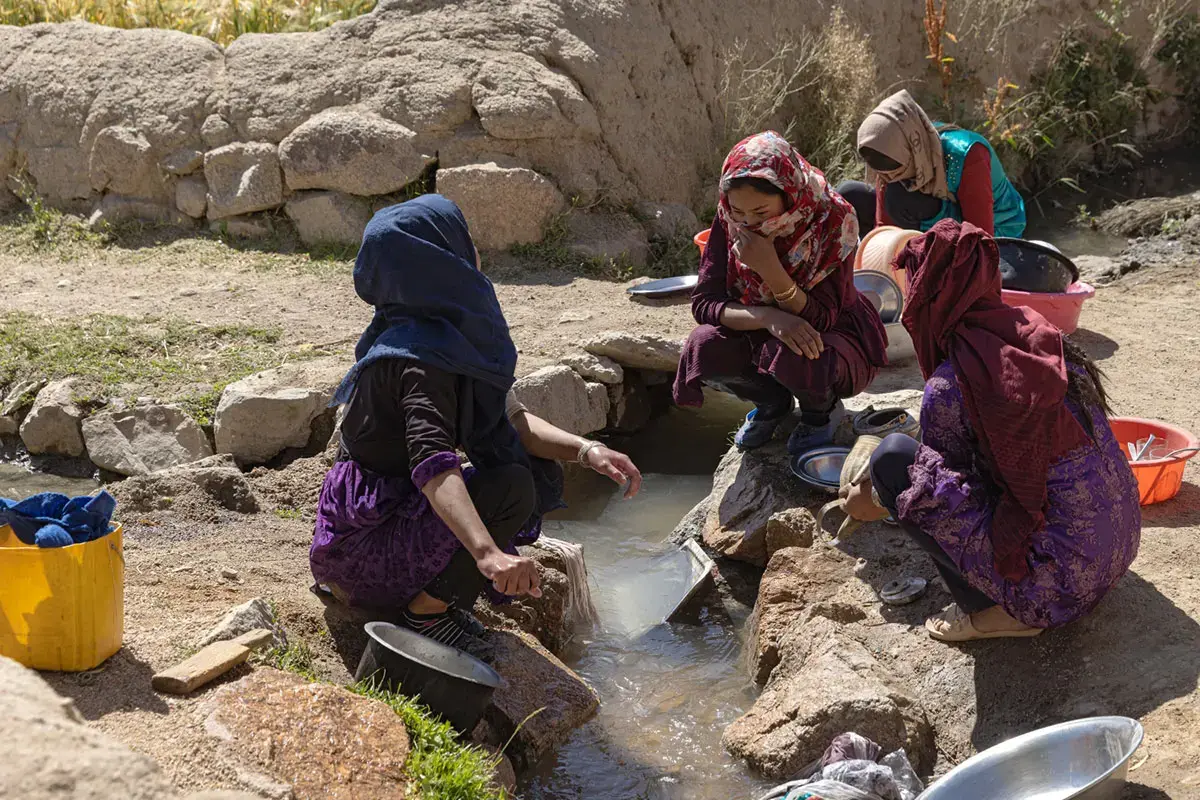Afghan women gathered together and washing cookware