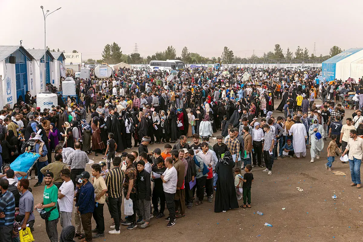 Afghans queue for processing and to receive immediate assistance near the town of Islam Qala, in western Afghanistan, after crossing the border with Iran. Temperatures in summer reach the high 30s Celsius (around 99 Fahrenheit). Women and girls report having to wait for hours in the sun and heat. Photo: UN Women/Sayed Habib Bidell