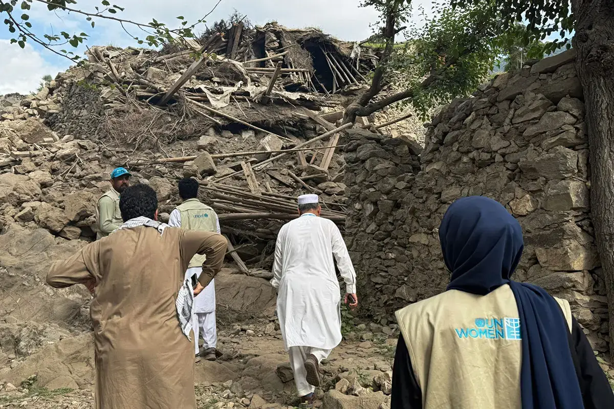 A group of people walk through the crumbled remains of buildings after an earthquake