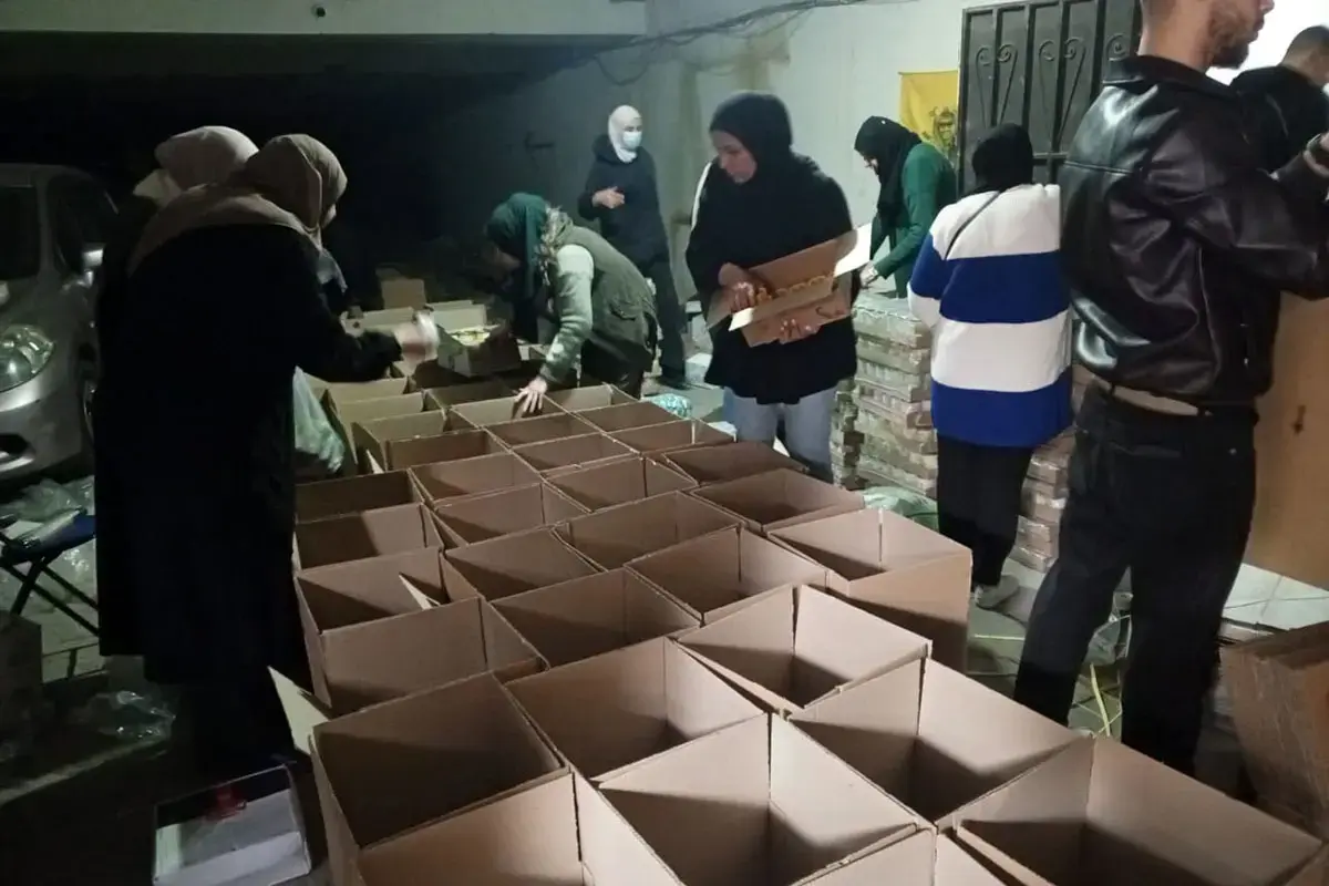 Women assemble and pack food parcels in boxes as part of a distribution effort.