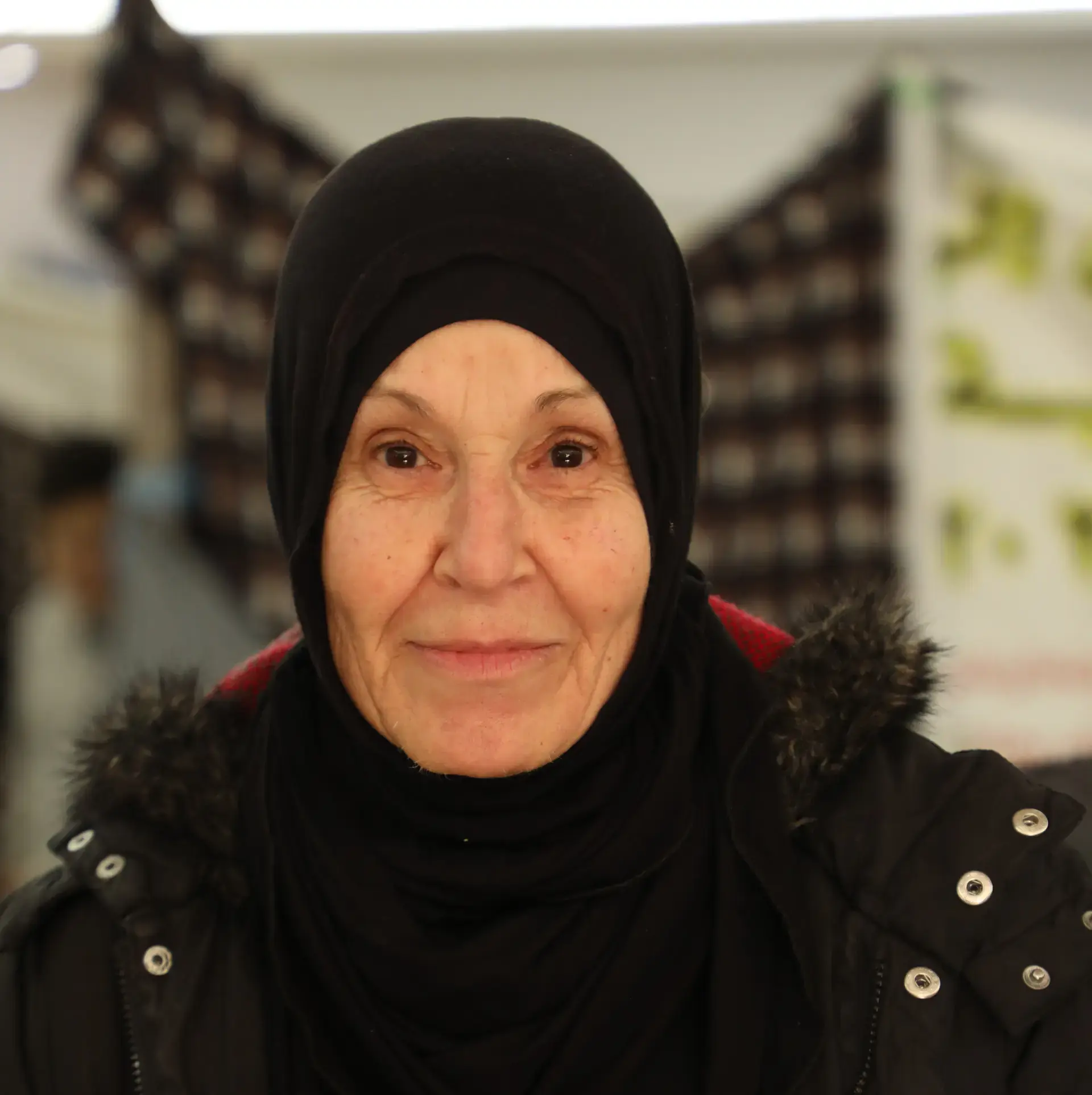 Portrait of an older woman in a black headscarf looking directly at the camera.