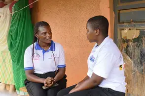 A young Ugandan woman sits with another local woman to talk