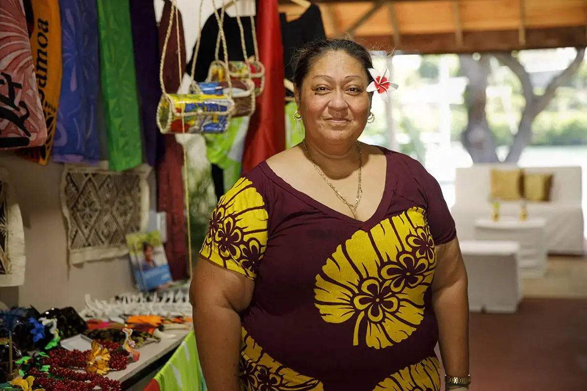 A portrait of a woman market vendor, posing with a hibiscus flower behind her ear