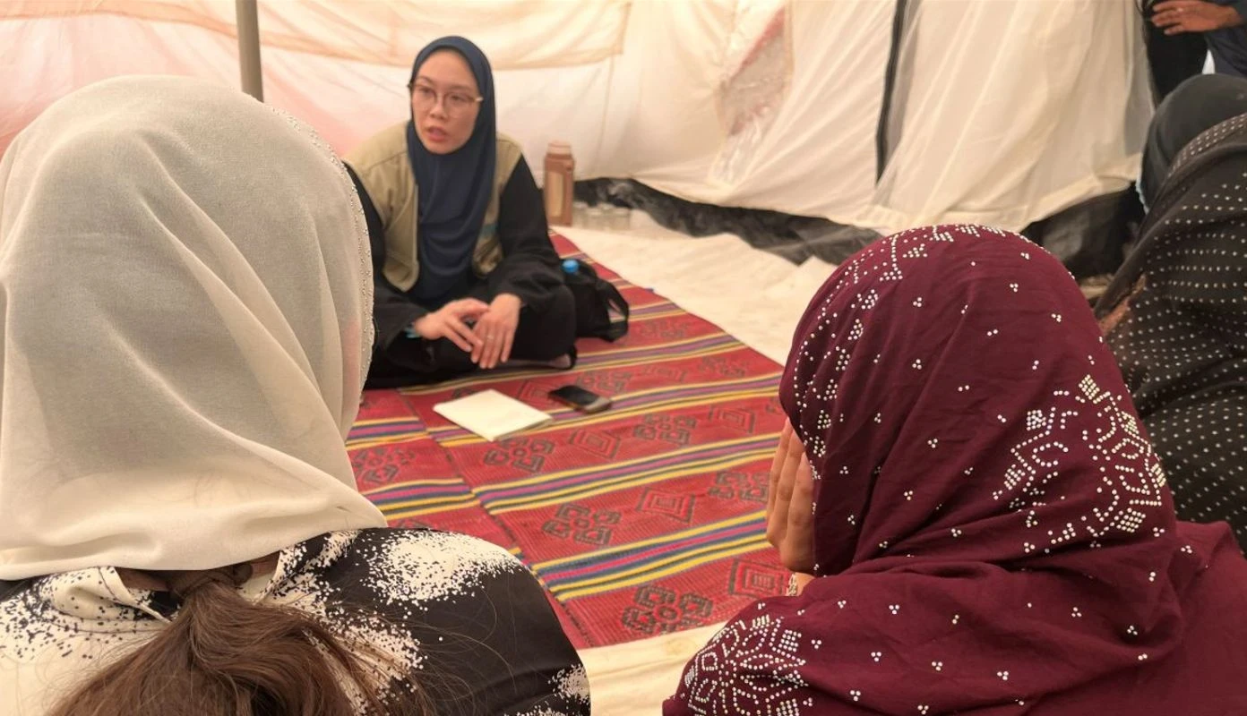 A young woman with glasses speaks with women in a remote Afghan village