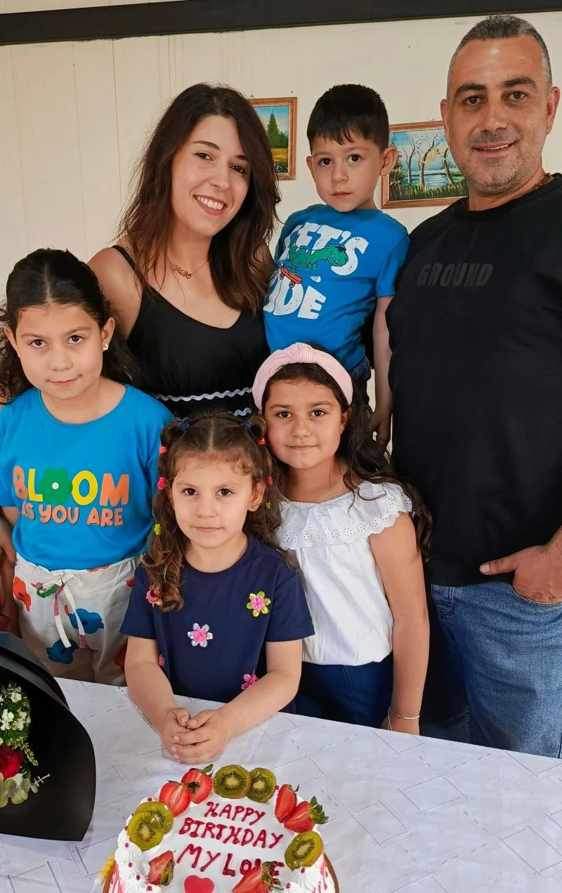 A young family poses together with a birthday cake