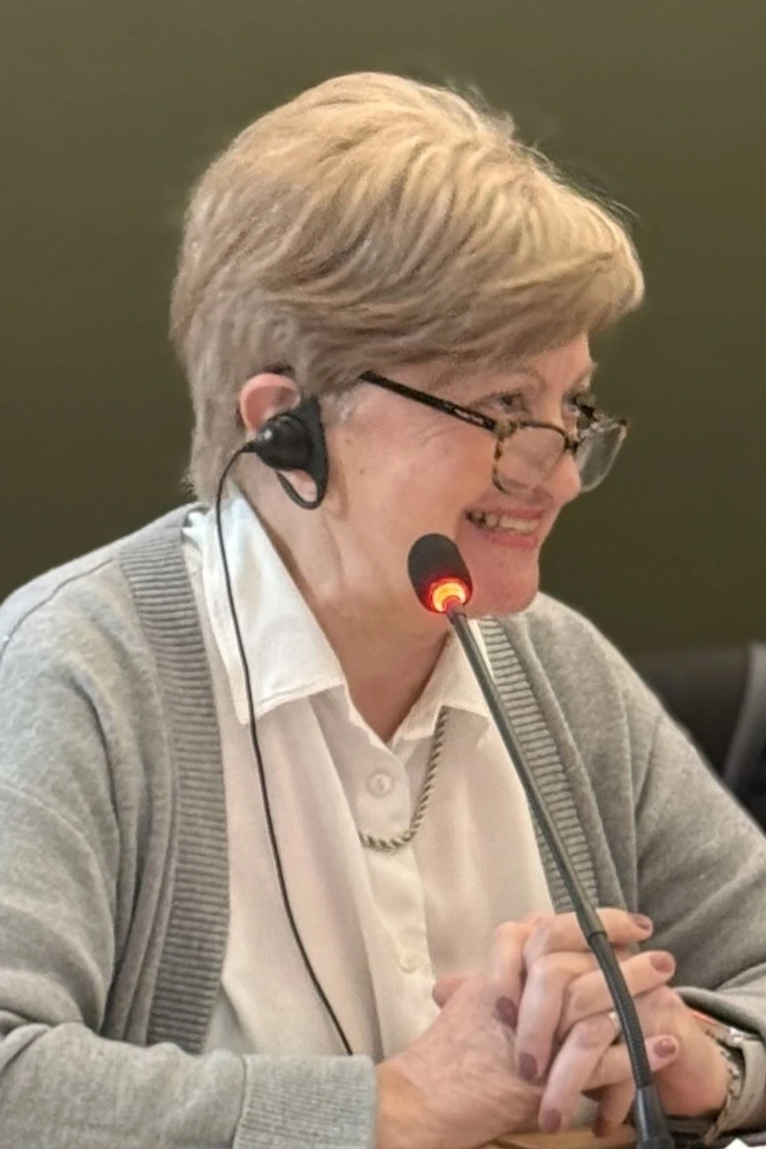 A woman smiles and speaks into a microphone
